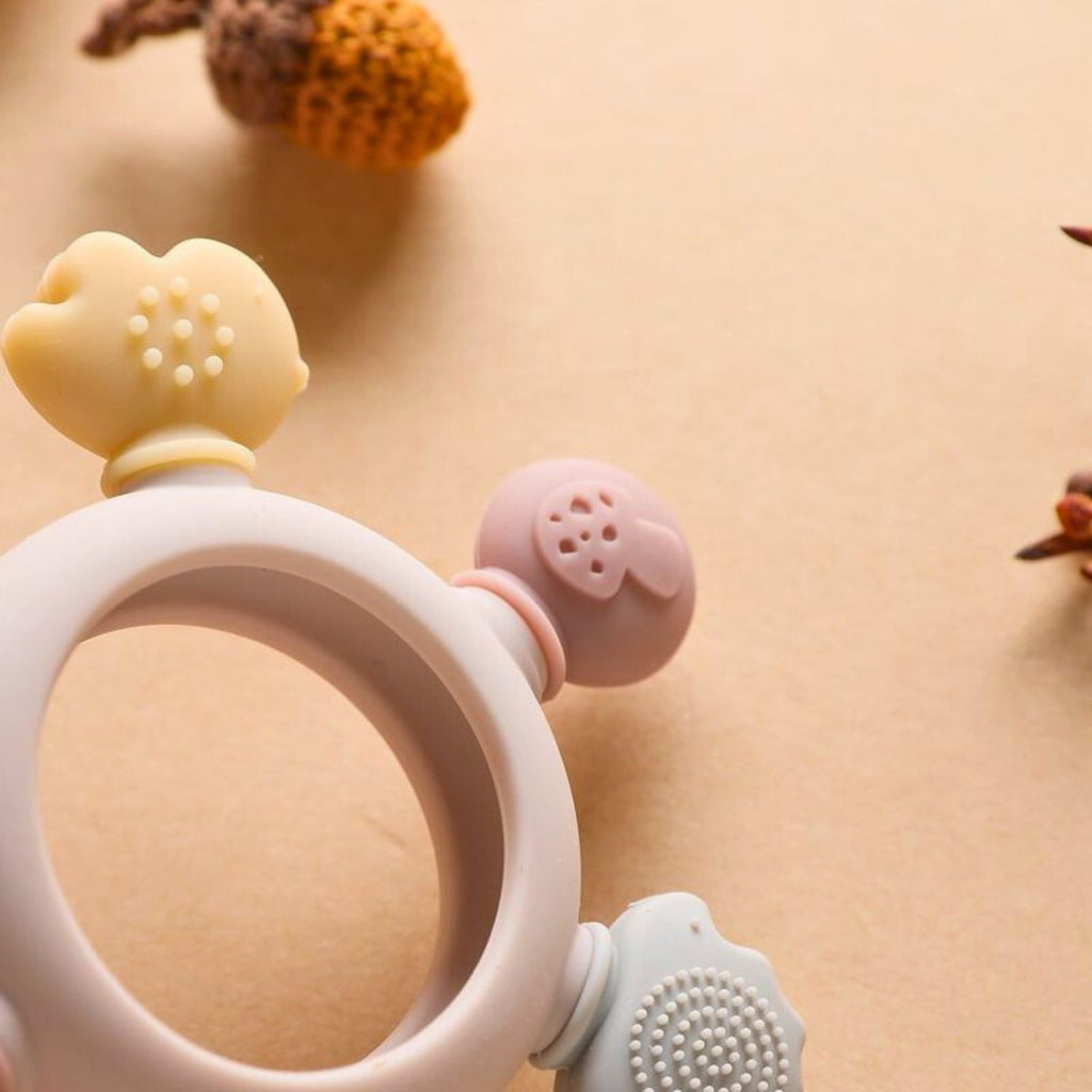 Baby silicone teether color pink with wooden ring and rattle